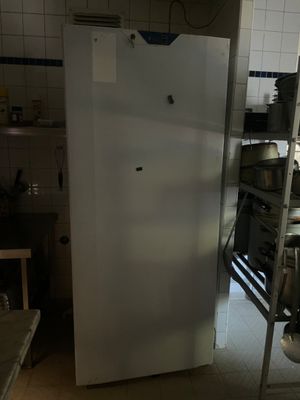 un réfrigérateur blanc dans une petite cuisine, à côté d'une cuisinière