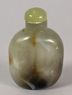 a small glass bottle with a green top on a white surface