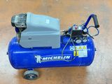 a blue air compressor sitting on top of a wooden floor