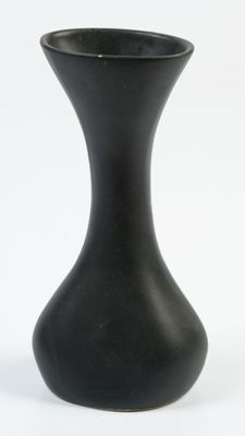 un vase noir posé sur une surface blanche