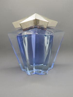 un flacon de parfum bleu avec un bouchon doré, posé sur une surface grise
