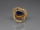 a close up of a gold ring with a blue stone in it