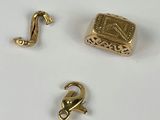 trois bijoux en or posés sur une surface blanche