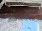 une petite horloge blanche posée sur une boîte en bois, elle-même posée sur une table