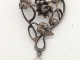 une image représentant une broche ornée de perles et de fleurs sur fond blanc