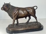 statue en bronze représentant un taureau, posée sur un socle en marbre, sur une surface blanche