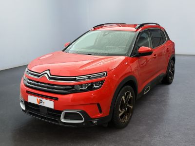 La voiture rouge est garée dans une grande pièce au sol noir.
