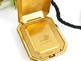 a gold plated pocket watch with a black cord around it
