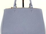 a blue handbag on a white background with a brown handle