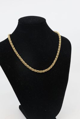 a gold chain necklace on a black mannequin