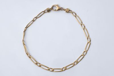 gros plan d'un bracelet en chaîne en or sur fond blanc
