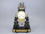 une horloge noire et dorée surmontée d'un oiseau