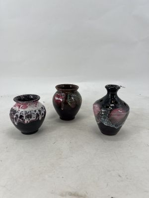 three small vases sitting on a white surface with a white background
