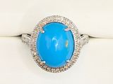 a close up of a ring with a blue stone surrounded by diamonds