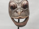 une image représentant un masque à l'aspect inquiétant posé sur un socle
