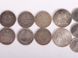 Plusieurs types de pièces de monnaie sont disposés en rangée sur une surface blanche