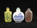 trois bouteilles en verre de couleurs différentes posées les unes à côté des autres sur une surface noire