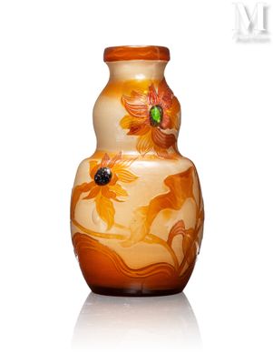 un vase orange orné de fleurs, posé sur une surface blanche