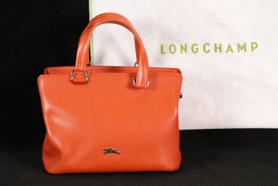 un gros plan d'un sac à main Longchamp à côté d'un sac blanc
