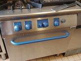 une cuisinière en acier inoxydable avec une poignée bleue dans une cuisine