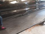 a woman standing next to a black car in a garage