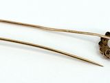 two gold hair pins on a white surface