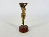 une petite statue en bronze représentant une femme, posée sur un socle en marbre