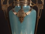 a blue vase with a gold handle on a black background