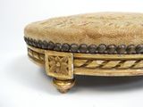 un pouf doré orné de perles, posé sur un fond blanc