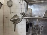 une cuisine équipée d'un évier, d'une cuisinière et de casseroles et poêles accrochées au mur