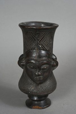 a black vase with a face on the top of it
