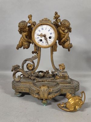 a gold clock with cherensils and angels on it