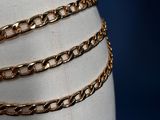 a close up of a mannequin torso with a gold chain belt