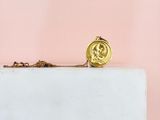 a gold necklace with a coin on it sitting on top of a marble block
