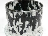un gros plan d'un vase noir et blanc posé sur une surface blanche