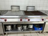 un plan de travail en acier inoxydable sur lequel sont posés des casseroles et des poêles, dans une cuisine professionnelle