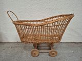 an old fashioned wicker baby stroller with wheels on a sidewalk