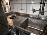 un évier en acier inoxydable dans une cuisine, à côté d'un plan de travail