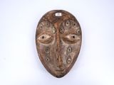 un masque en bois accroché à un mur, sur fond blanc