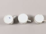 two cups and a saucer are sitting side by side on a gray surface