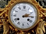 a gold clock with roman numerals on the face of it