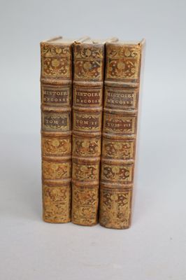 three old books sitting on top of each other on a white surface