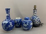 trois vases bleus et blancs et une lampe posés sur une table
