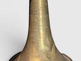 a brass bell with writing on it sitting on a table