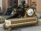 a statue of a woman sitting on a bench with a clock