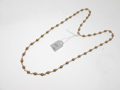 un gros plan d'un collier composé de perles dorées, orné d'une étiquette
