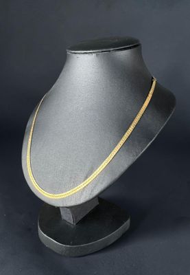 un collier en or posé sur un mannequin noir, devant un fond noir
