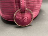 the pink purse has a metal ring on the front of it