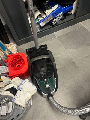 a vacuum that is sitting on the floor next to a pile of cleaning supplies