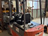 un chariot élévateur dans un entrepôt où il y a beaucoup de bois